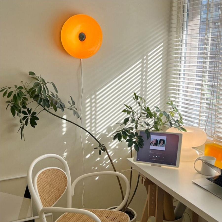 Estudio con lámpara donut naranja en la pared